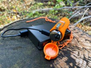 Portable camping flashlight and power bank on tree stump.