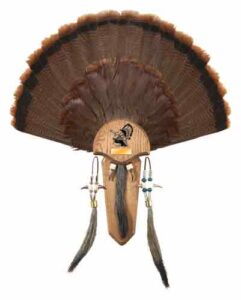 Decorative wooden wall fan with feathers and beads.