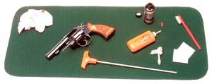 Gun cleaning kit with revolver on green mat.