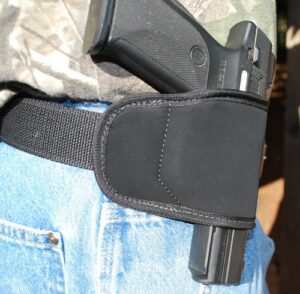Handgun holster on hip with belt.