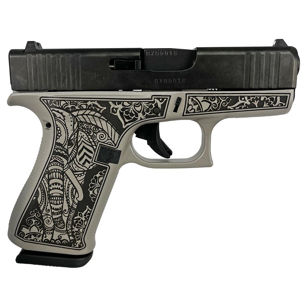 Engraved handgun with detailed black floral design.