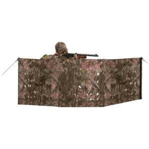 Hunter behind camouflage shooting blind with rifle.