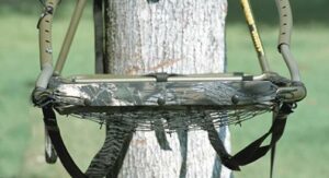 Tree stand with camouflage netting on tree trunk