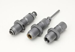 Three metallic machine parts on white background.