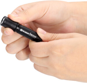 Hands holding compact black flashlight device