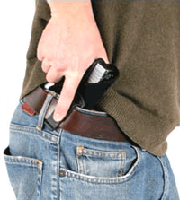 Person holstering pistol in waistband of jeans.