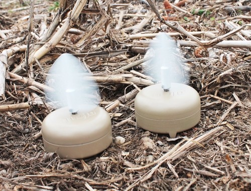Two outdoor mosquito repellent diffusers emitting mist