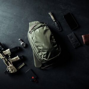 Tactical backpack with gear on dark surface.