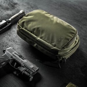 Green tactical pouch with firearm on black surface.