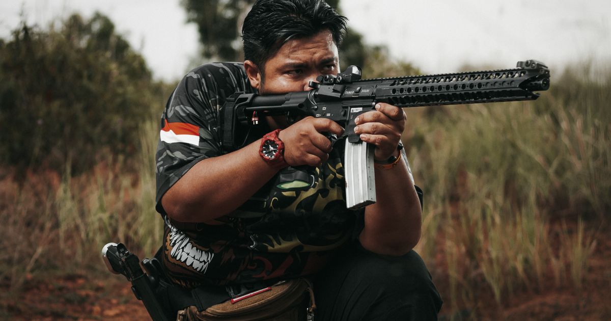 Shooter aiming an AR-15 rifle at an outdoor shooting range