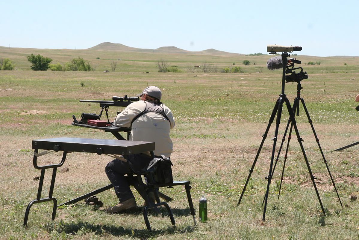 Bolt-action hunting rifle positioned for a long-range shot in open country